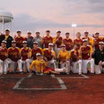 The ISU Baseball team poses by doing the "Number One" sign with their fingers at home plate with a trophy in front of the team.