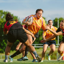 A female rugby player attempts to get past two oncoming defenders.