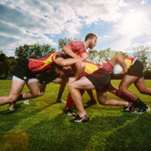 Two rugby teams struggle against each other to move the ball up field.