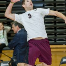 A male volleyball player about to spike a ball.