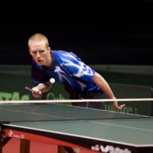 A male table tennis player focuses on the ball as he hits back to his competitor.